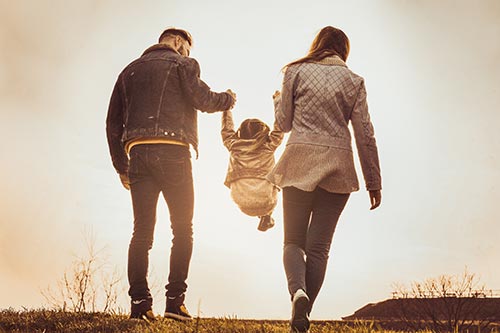 parents holding child while child swings between their arms